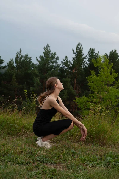 Siyah elbiseli güzel kız ormanda oturuyor.