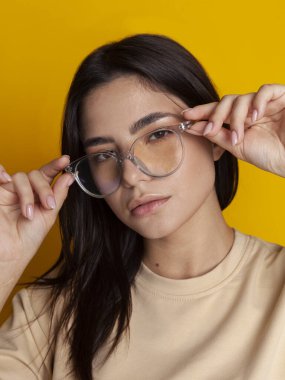 Sarı arka planda gözlüklü güzel bir esmerin portresi.