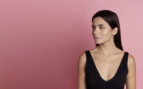 Pembe arka planda spor giyimli güzel bir kız.