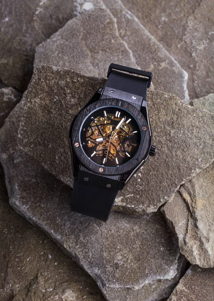 Siyah adamın saatleri taşların arkasında yatıyor.