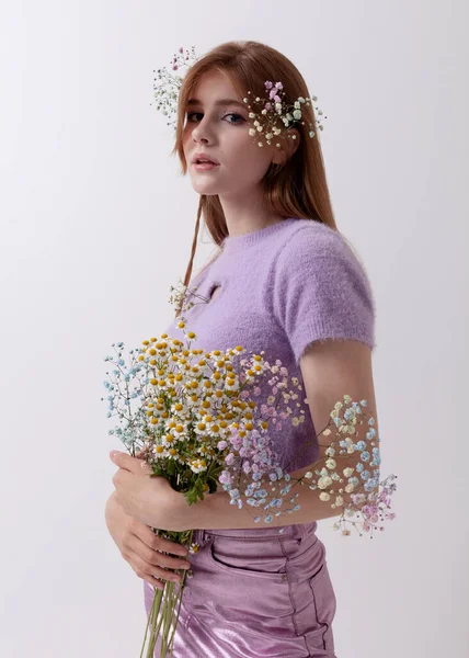 2000 'li yılların kıyafetleri içinde açık arkaplanda bir buket çiçekle kızıl saçlı kız.