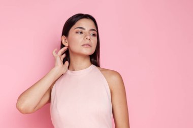 Pembe arka planda açık pembe elbisesi olan güzel esmer.