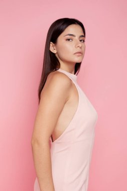 Pembe arka planda açık pembe elbisesi olan güzel esmer.