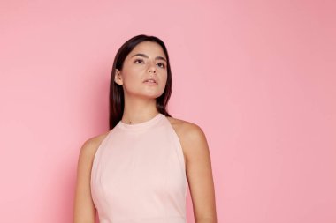 Pembe arka planda açık pembe elbisesi olan güzel esmer.