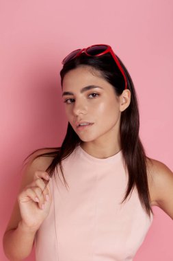 Pembe arka planda parlak güneş gözlüklü güzel esmer