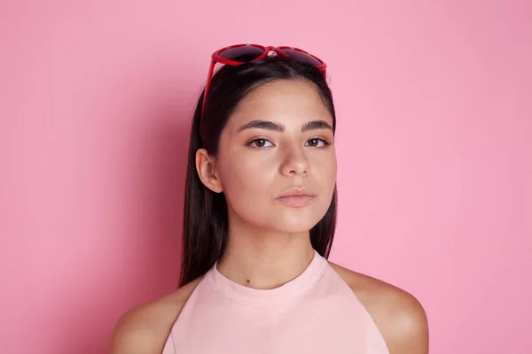 Pembe arka planda parlak güneş gözlüklü güzel esmer