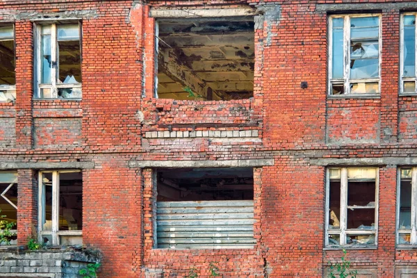 Abandoned building. A fragment of an old abandoned red brick building with broken windows.