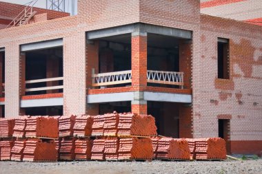 İnşaat halindeki çok katlı tuğlalı bir binanın ön cephesi..