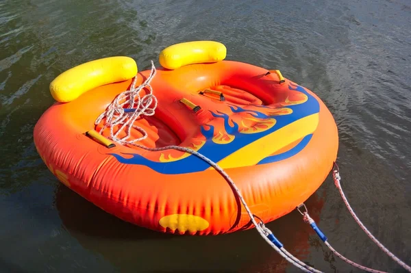 Double inflatable rubber boat of orange color on the water surface.
