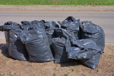 Şehir caddesinde çöp dolu siyah plastik torbalar..