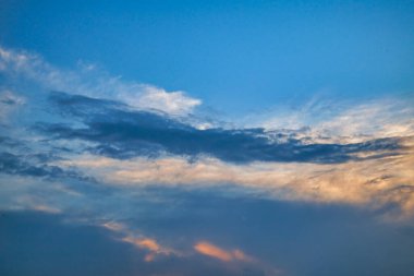 Akşam gökyüzü resimli bulutlarda, batan güneşin ışınlarıyla aydınlatılıyor..