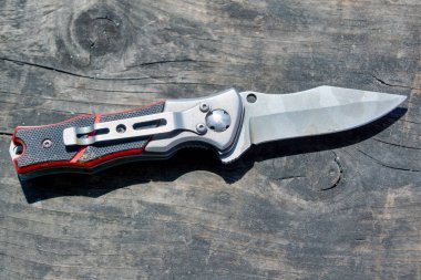 Ahşap masa arkasında çakı var. Ahşap bir masanın arka planında eski bir katlama bıçağı..