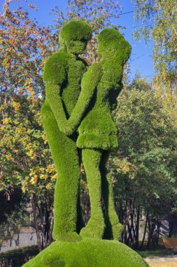 Şehir parkındaki yapay çimlerden yapılmış kentsel bir heykel. Genç bir adam ve aşık bir kız..