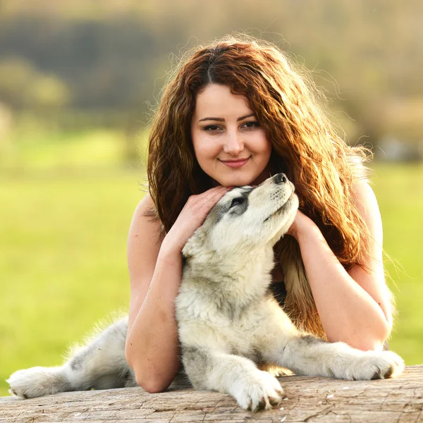 Όμορφη γυναίκα με νεαρό σκύλο Malamute — Φωτογραφία Αρχείου