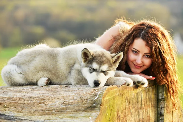 Hermosa mujer con perro joven Malamute — Foto de Stock
