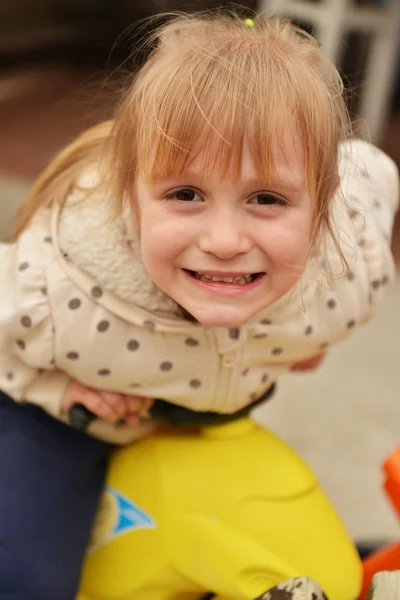 Menina feliz em uma bicicleta de brinquedo — Fotografia de Stock