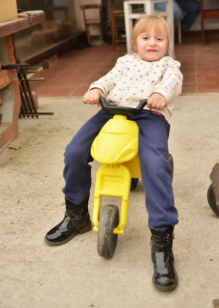 Menina feliz em uma bicicleta de brinquedo — Fotografia de Stock