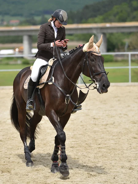 Mujer usando teléfono inteligente mientras monta a caballo —  Fotos de Stock