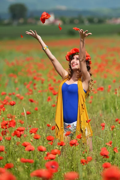 Kvinna poserar i blommande vallmo fält — Stockfoto