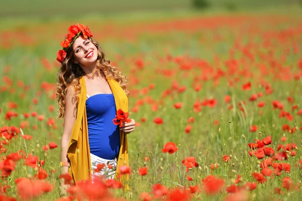 Kvinna poserar i blommande vallmo fält — Stockfoto