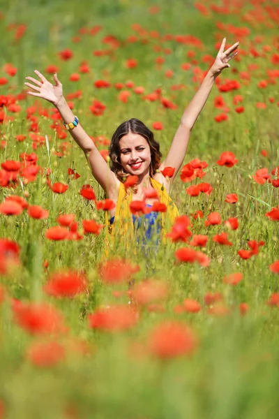 Kvinna poserar i blommande vallmo fält — Stockfoto