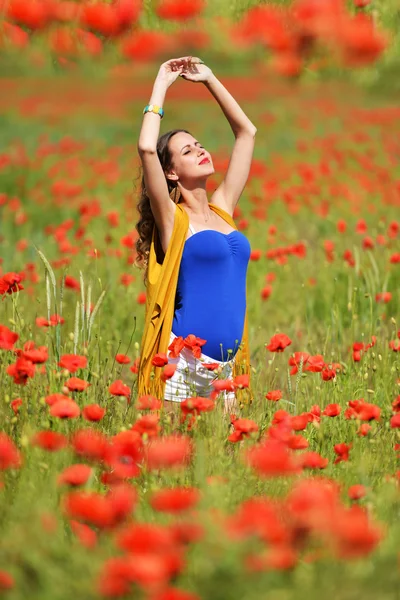 Kvinna poserar i blommande vallmo fält — Stockfoto