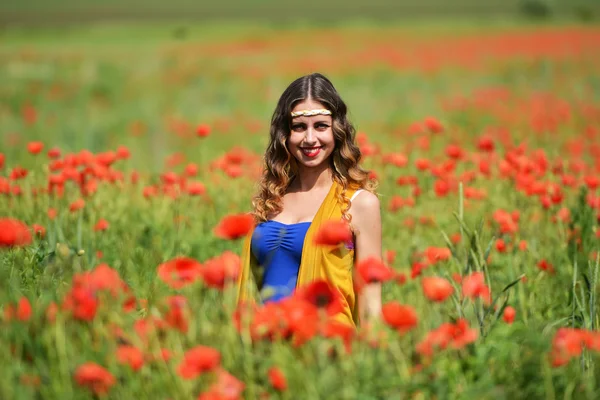 Kvinna poserar i blommande vallmo fält — Stockfoto