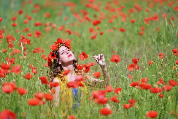 Kvinna poserar i blommande vallmo fält — Stockfoto