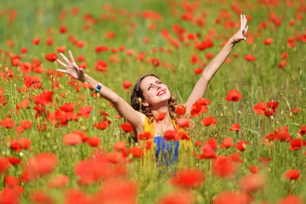 Kvinna poserar i blommande vallmo fält — Stockfoto