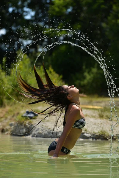 Femme dans l'eau agitant les cheveux — Photo