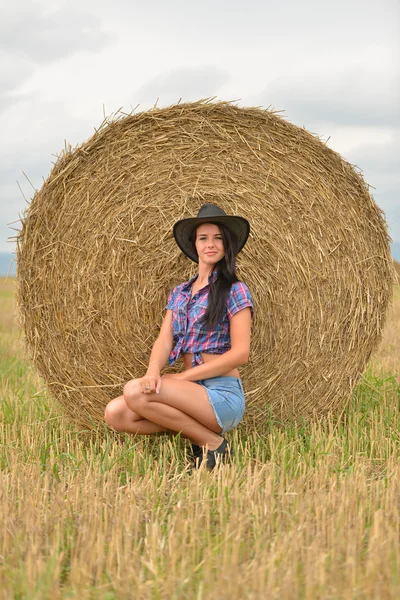 Mladí cowgirl snění v poli seno — Stock fotografie