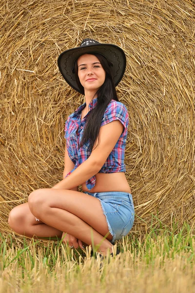 Een jonge cowgirl dagdromen in een veld van hooi — Stockfoto