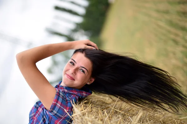 Uma jovem vaqueira sonhando acordado em um campo de feno — Fotografia de Stock