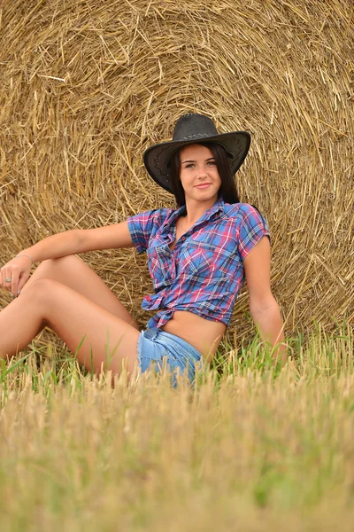 Une jeune cow-girl rêvant dans un champ de foin — Photo