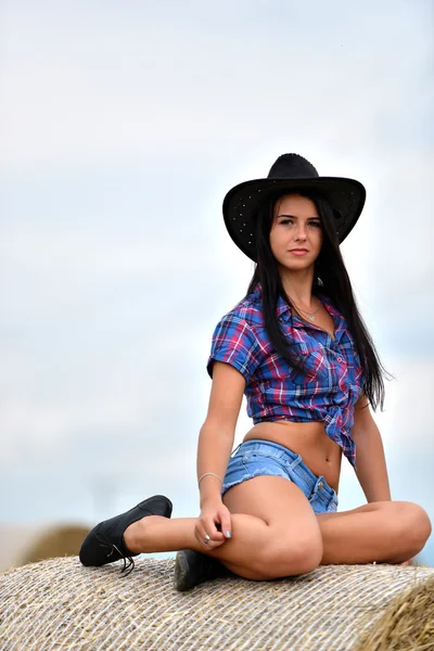 En ung cowgirl dagdrömmeri i ett hö-fält — Stockfoto