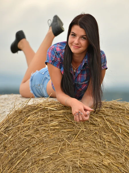 En ung cowgirl dagdrömmeri i ett hö-fält — Stockfoto