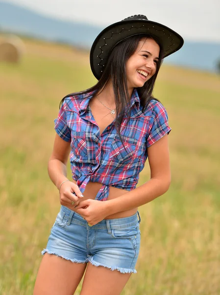 Een jonge cowgirl dagdromen in een veld van hooi — Stockfoto