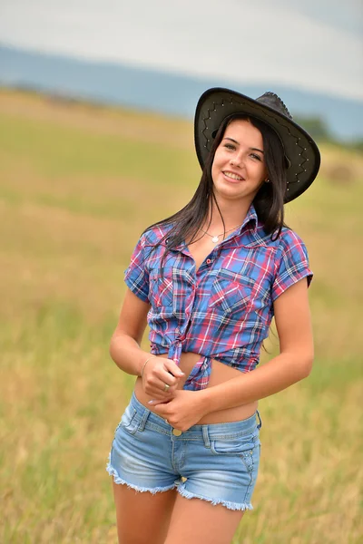 Een jonge cowgirl dagdromen in een veld van hooi — Stockfoto