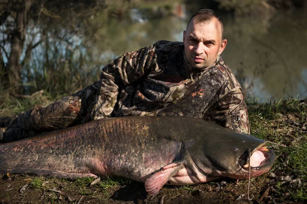 Fisherman holding a giant catfish. Catch of fish, freshwater fishing, monster fish