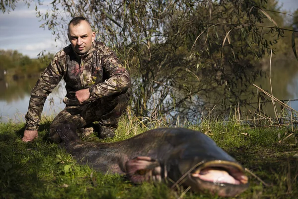 Fisherman holding a giant catfish. Catch of fish, freshwater fishing, monster fish