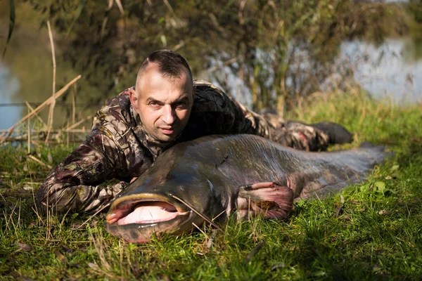 Fisherman holding a giant catfish. Catch of fish, freshwater fishing, monster fish