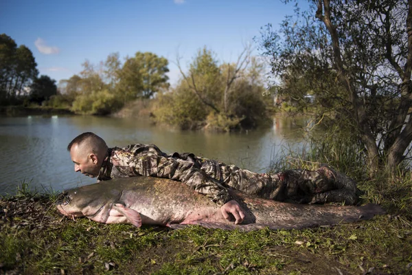 Fisherman holding a giant catfish. Catch of fish, freshwater fishing, monster fish