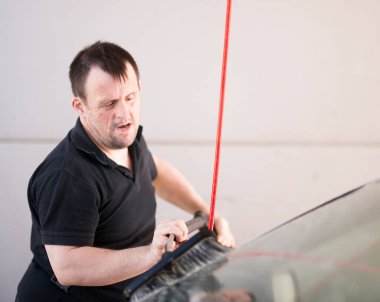 Down sendromlu bir adam arabayı yıkıyor.