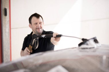 Down sendromlu bir adam arabayı yıkıyor.