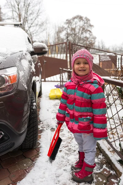 Meisje reinigt de sneeuw auto — Stockfoto