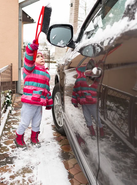 Kleines Mädchen putzt das Schneemobil — Stockfoto