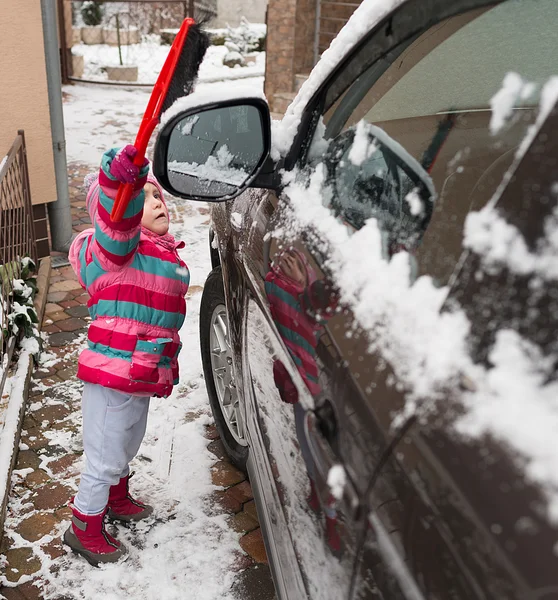 Meisje reinigt de sneeuw auto — Stockfoto