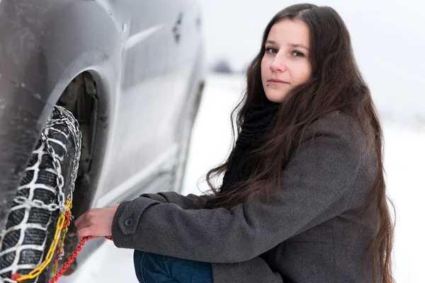 Vrouw zetten winter tire chains — Stockfoto