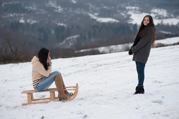 两个女朋友雪橇下坡 — 图库照片