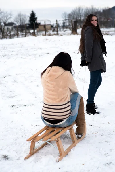 2 つのガール フレンドは下り坂そり — ストック写真